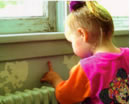 Photo of a baby girl scratching the wall next to the window