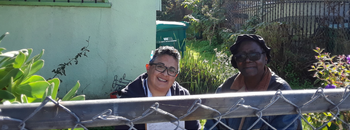 two people smiling looking over a fence